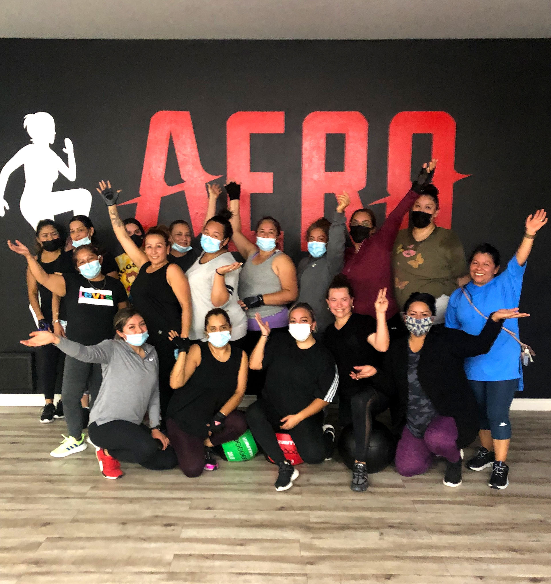 Aero gym-goers in front of the logo painted onto the gym's wall